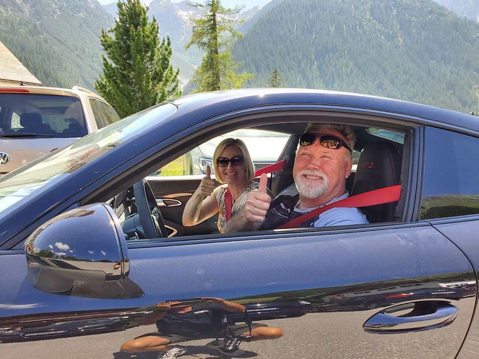 couple in porsche giving thumbs up